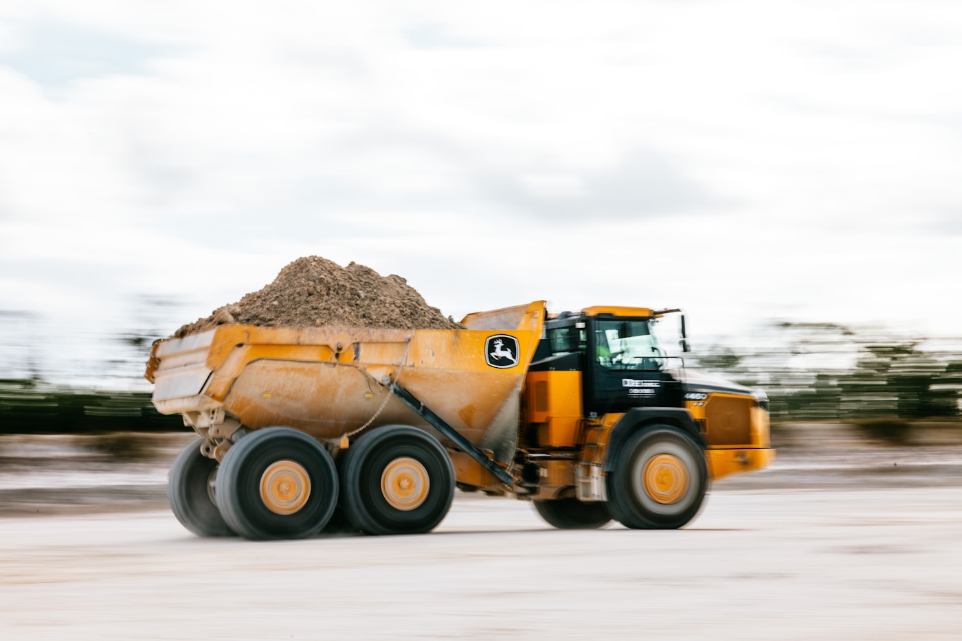 A yellow dump truck hauling material on site
