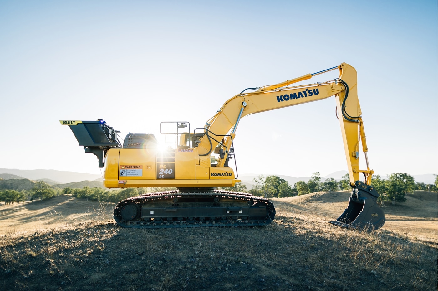 A yellow excavator on a dirt field at a development site